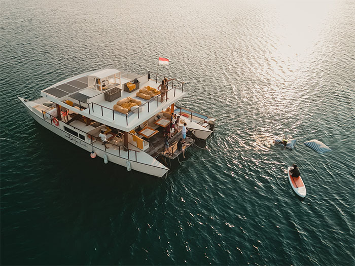 Utopia Catamaran cruise sailing in the Gili Islands with guests relaxing on deck