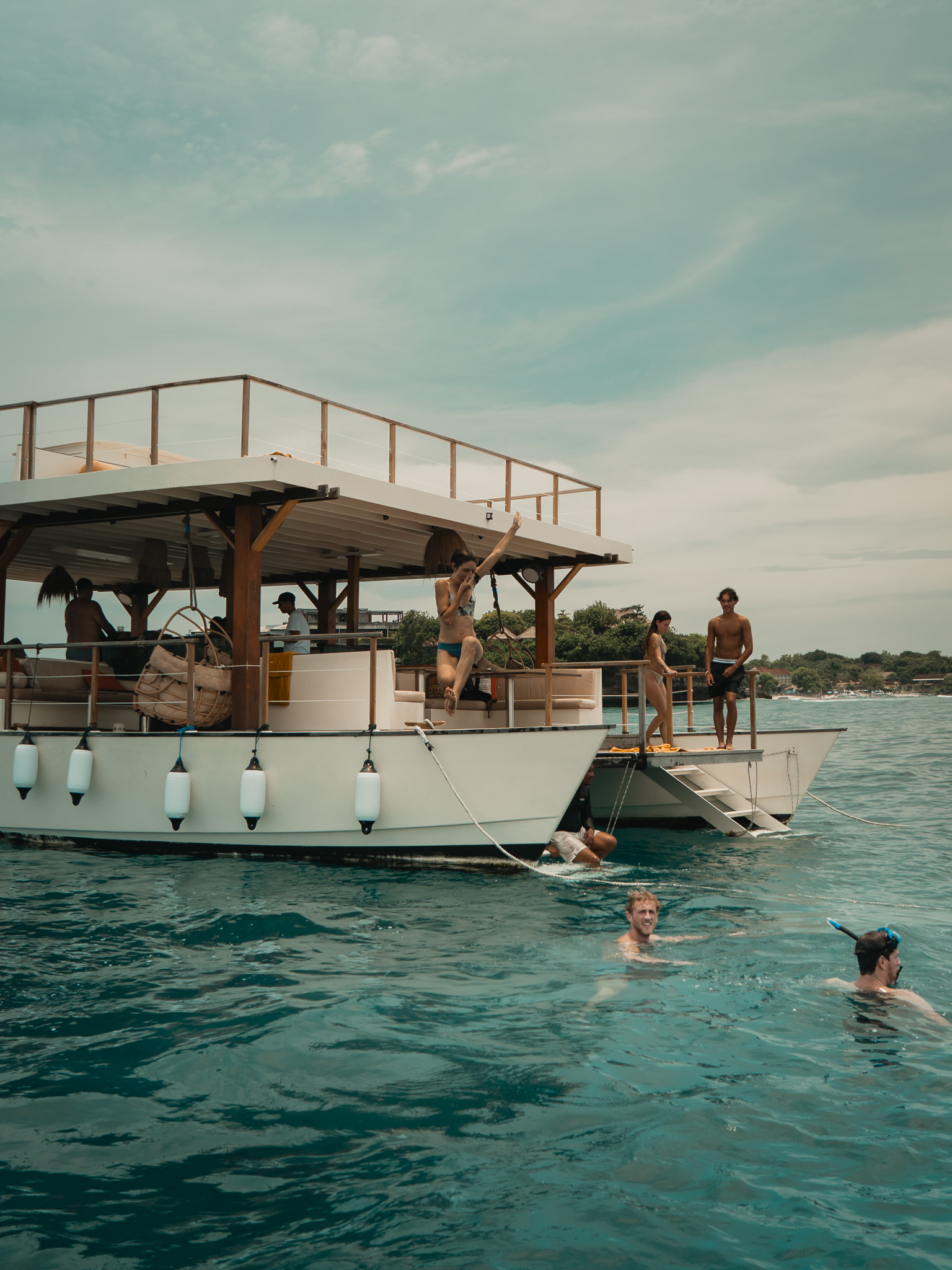 Guests swimming and relaxing and jumping off of Utopia catamaran in Nusa Lembongan Indonesia