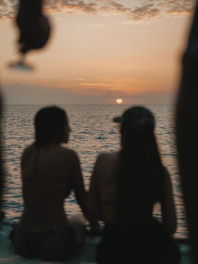 Couple watching the sunset on a private vs shared catamaran cruise decision — sunset sail aboard Utopia